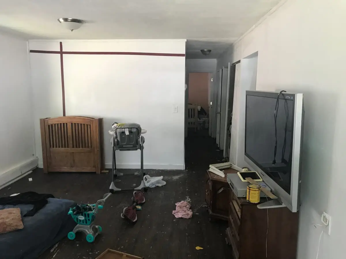 Selling a house after a life change in Mastic: living room with a crib, high chair and toys