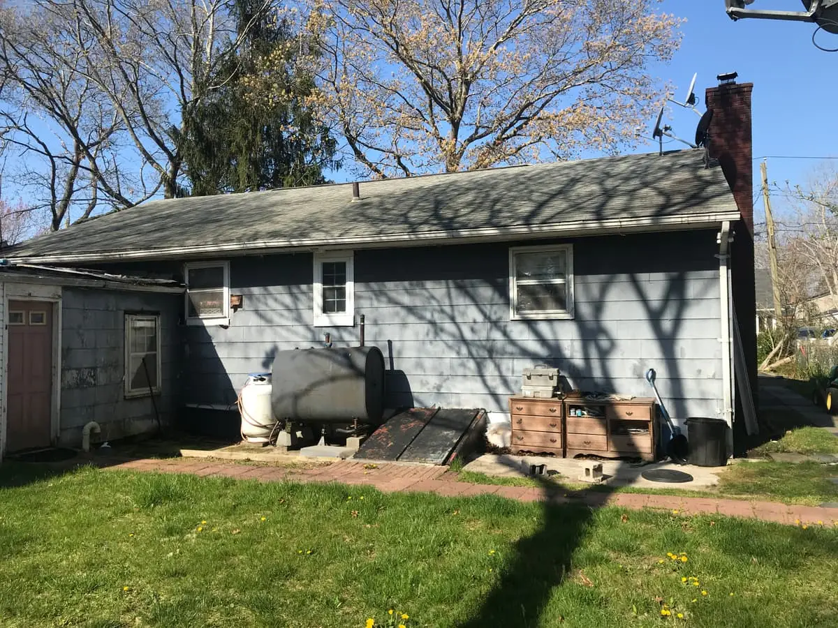 Selling a house with an oil tank in Mastic: rear of a ranch with an outdoor oil tank