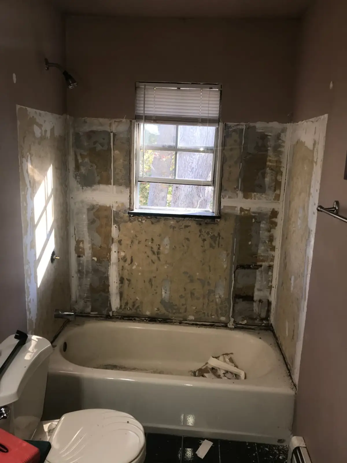 Selling a fire-damaged house in Mastic: tub surround torn off down to bare backing