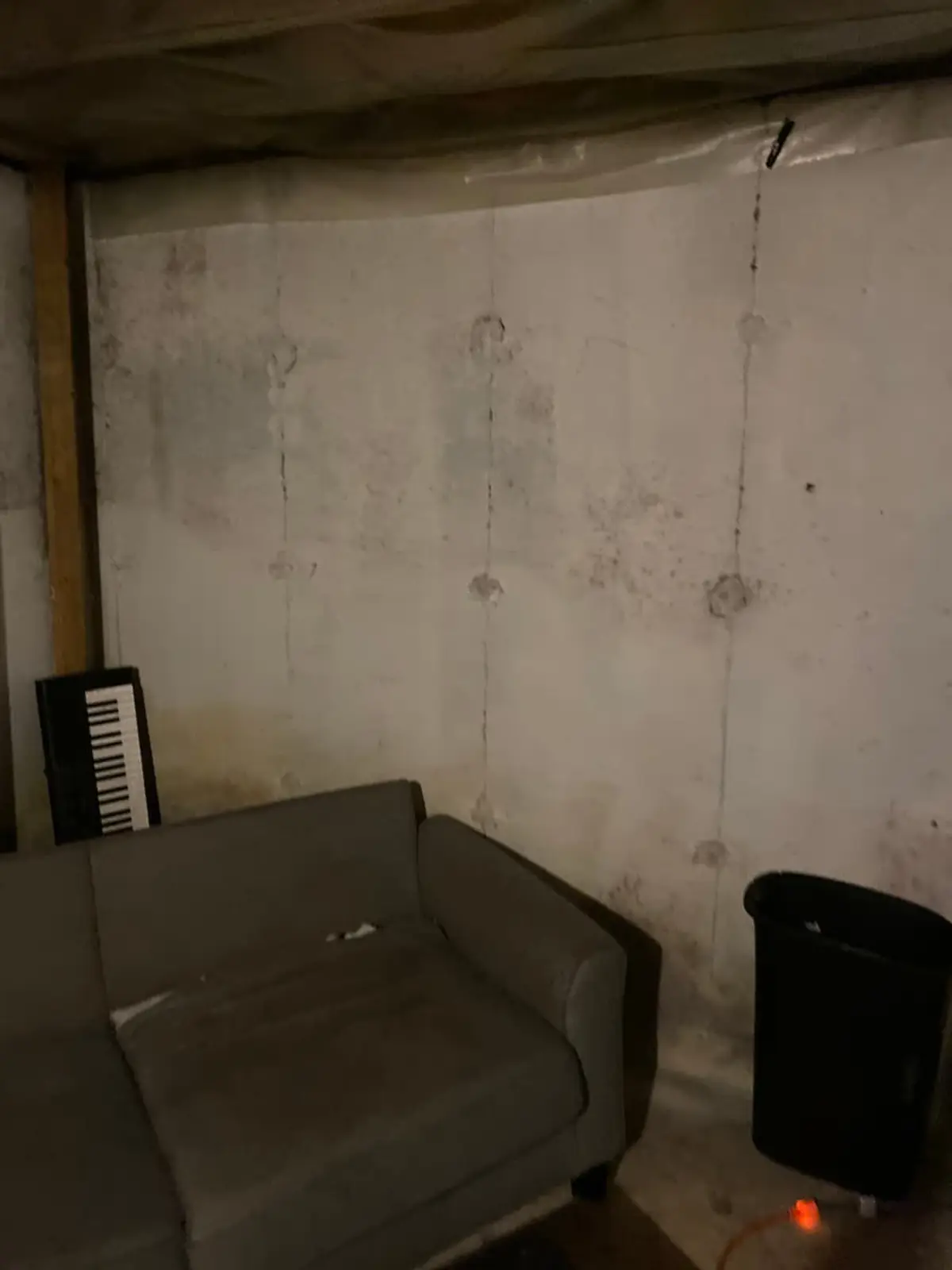 Selling a house during a divorce in Mastic: unfinished basement with a couch and stained walls